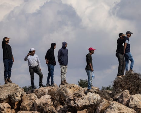 Palestinian men stand on a small rocky hill